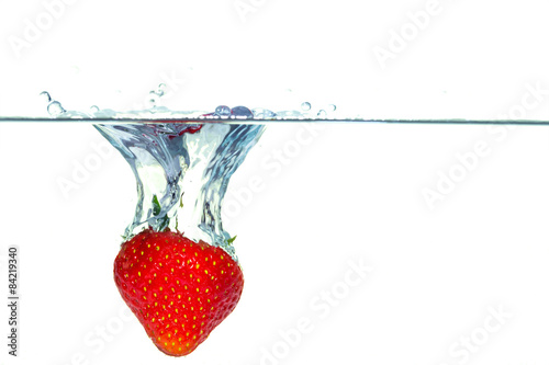 Strawberry falling into water with a splash