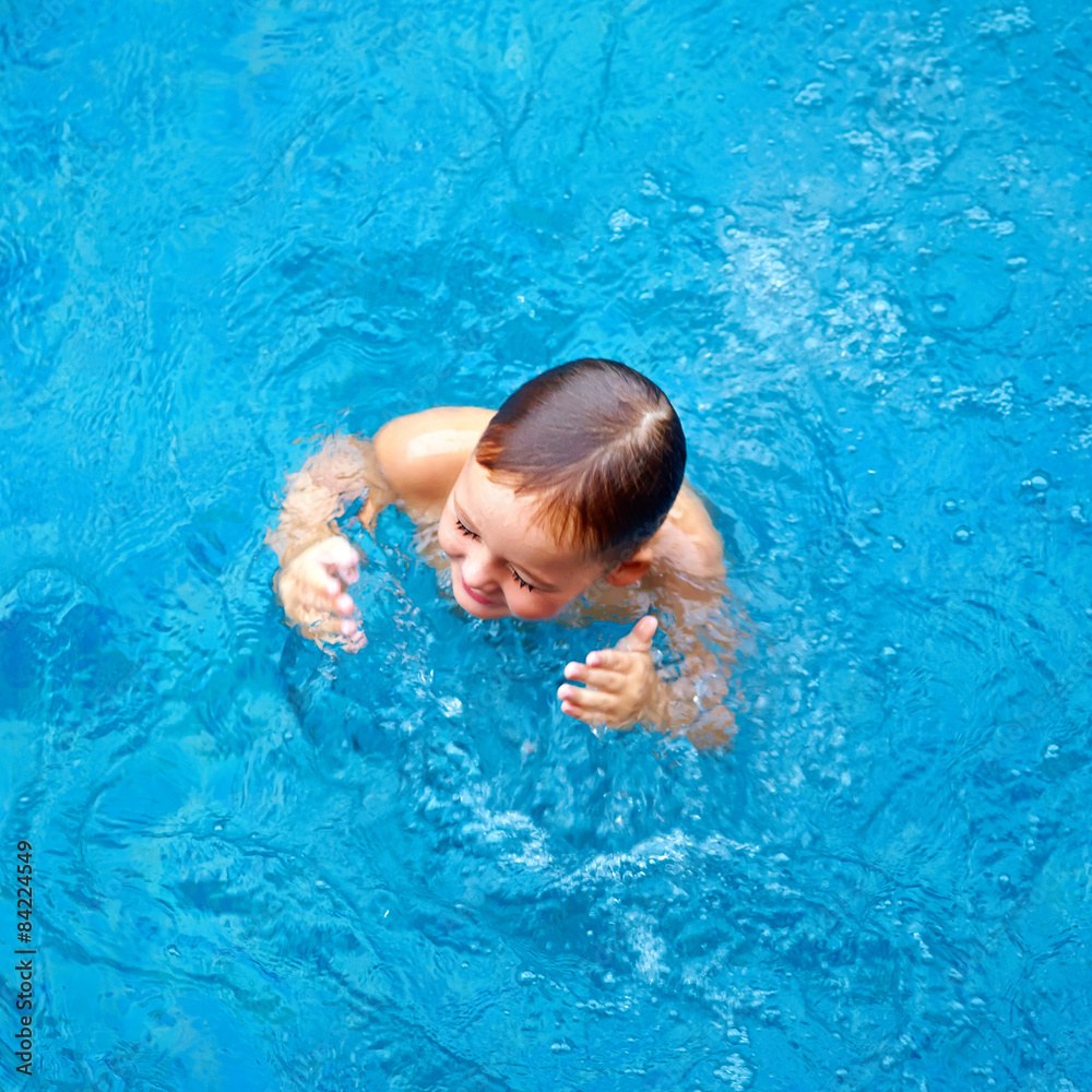 cute kid, boy dabbling in pool water, top view