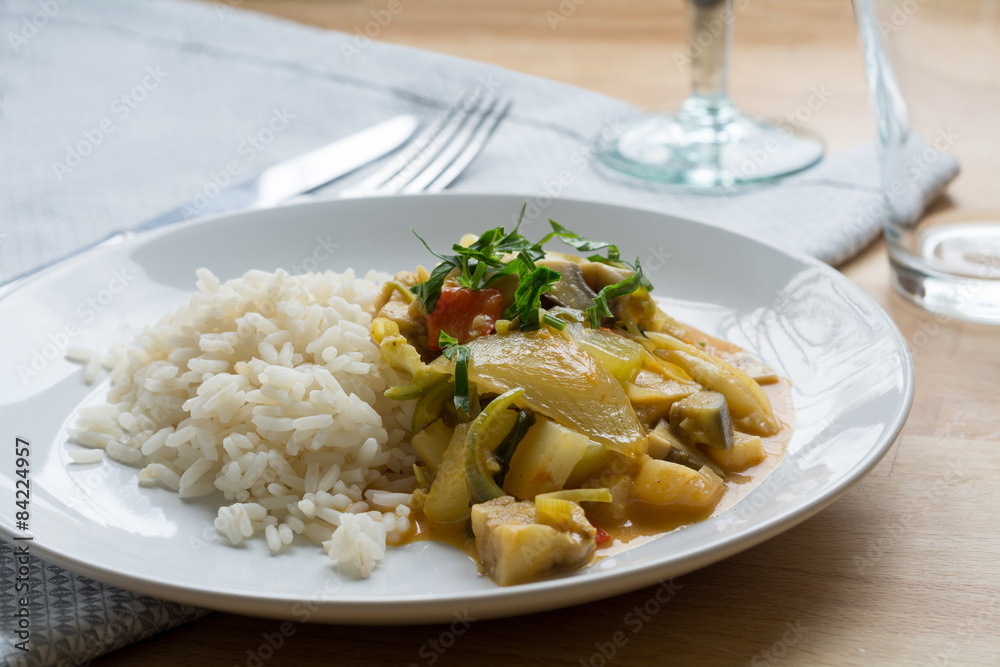 Yellow vegetable curry with rice on a white plate