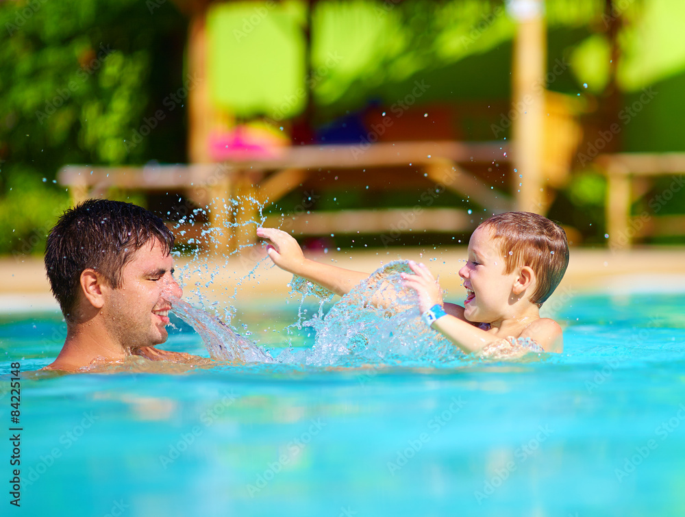 happy father and son dabbling in pool water, summer holiday happy father and son dabbling in pool water, summer holiday