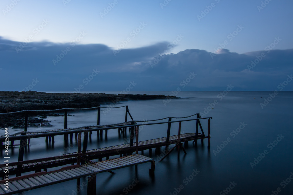 Long exposure: a wooden pier after sunset in a blu autumn sky