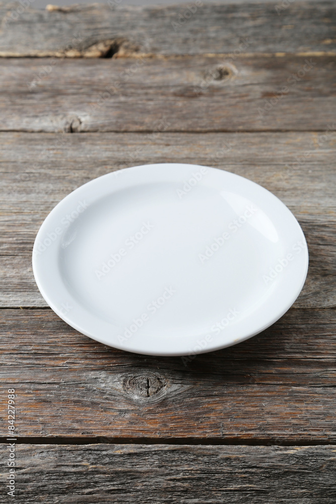 Empty white plate on grey wooden background Empty white plate on grey wooden background