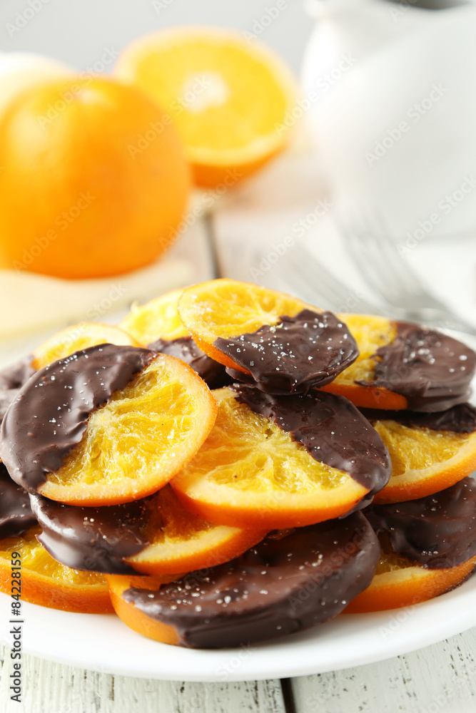 Delicious slices of orange coated chocolate on white background