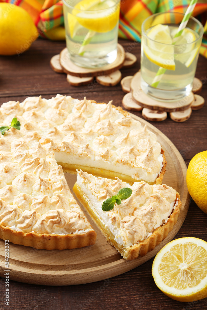 Lemon meringue pie on cutting board on  wooden background