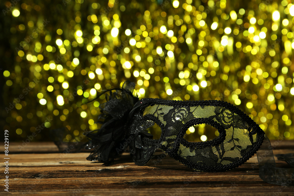 Female carnival mask with bokeh on brown wooden background Female carnival mask with bokeh on brown wooden background