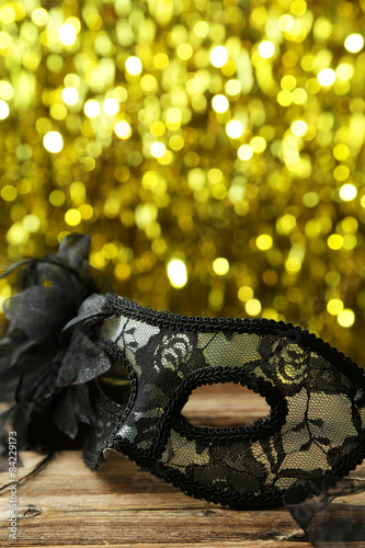 Female carnival mask with bokeh on brown wooden background