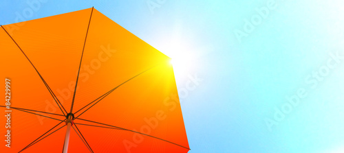 Orange sunshade with sun reflection in summer