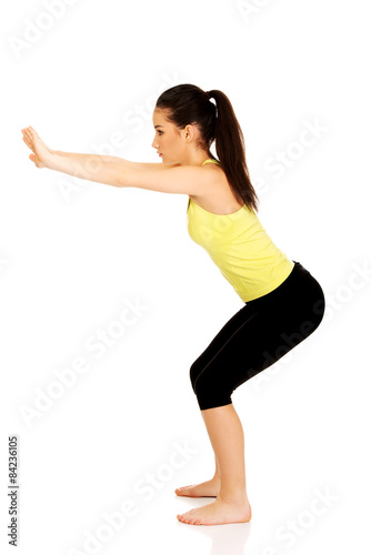 Young woman performs squats. 