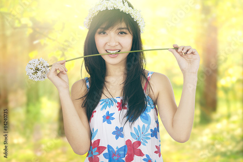 Pretty girl bites a dandelion in nature