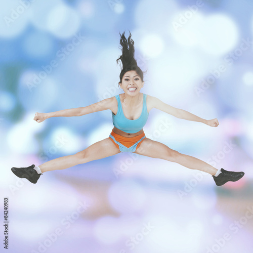 Sporty woman jumps over bokeh background