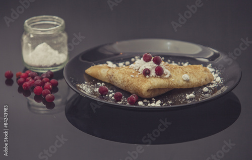 The pancakes are served on a black plate on a black background.