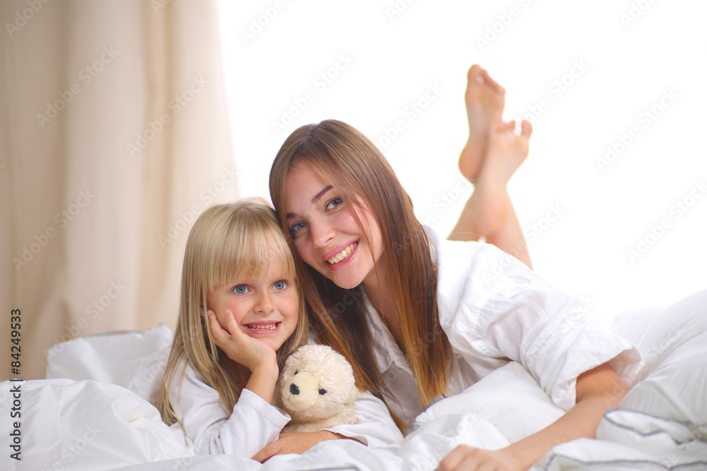 Woman and young girl lying in bed smiling Woman and young girl lying in bed smiling