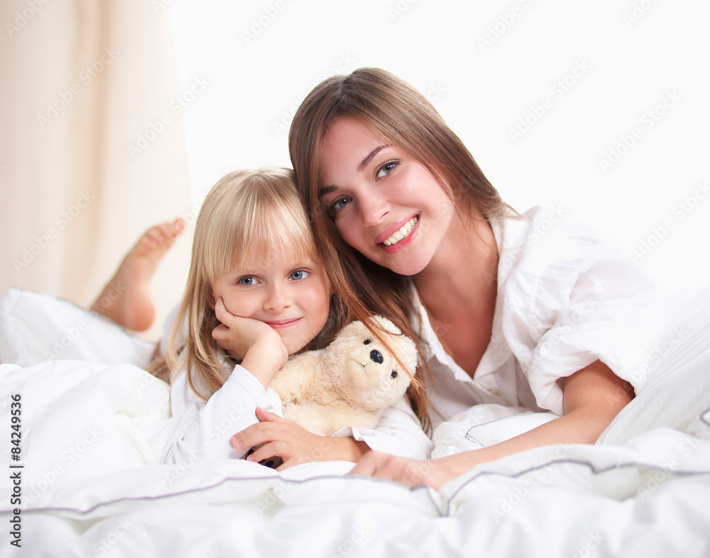 Woman and young girl lying in bed smiling Woman and young girl lying in bed smiling