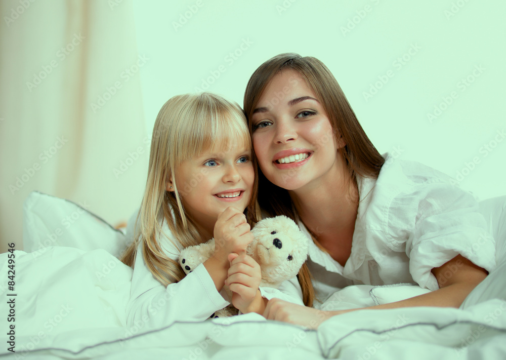 Woman and young girl lying in bed smiling Woman and young girl lying in bed smiling