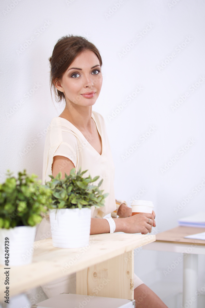 Attractive young businesswoman standing near desk in the office Attractive young businesswoman standing near desk in the office