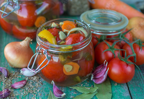 Open glass jar of tasty canned tomatoes