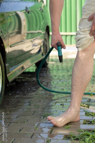 Men's feet, wash with a garden hose photo