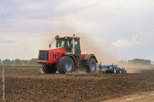 Color photo of a red tractor against the blue sky.