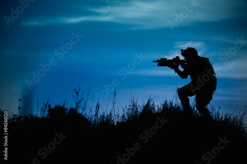 Silhouette of military soldier or officer with weapons at night.