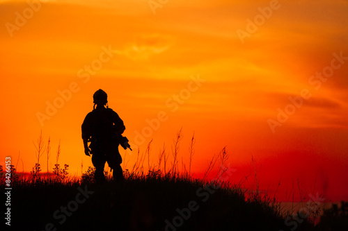 Silhouette of military soldier or officer with weapons at sunset © kaninstudio