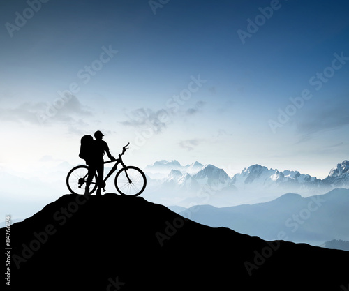 Silhouette of a bike tourist on mountain peak