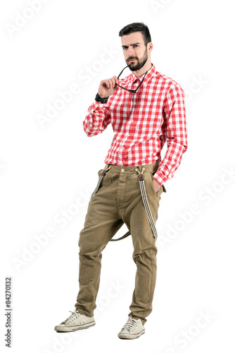 Фотография Young hipster with distrustful look at camera holding sunglasses