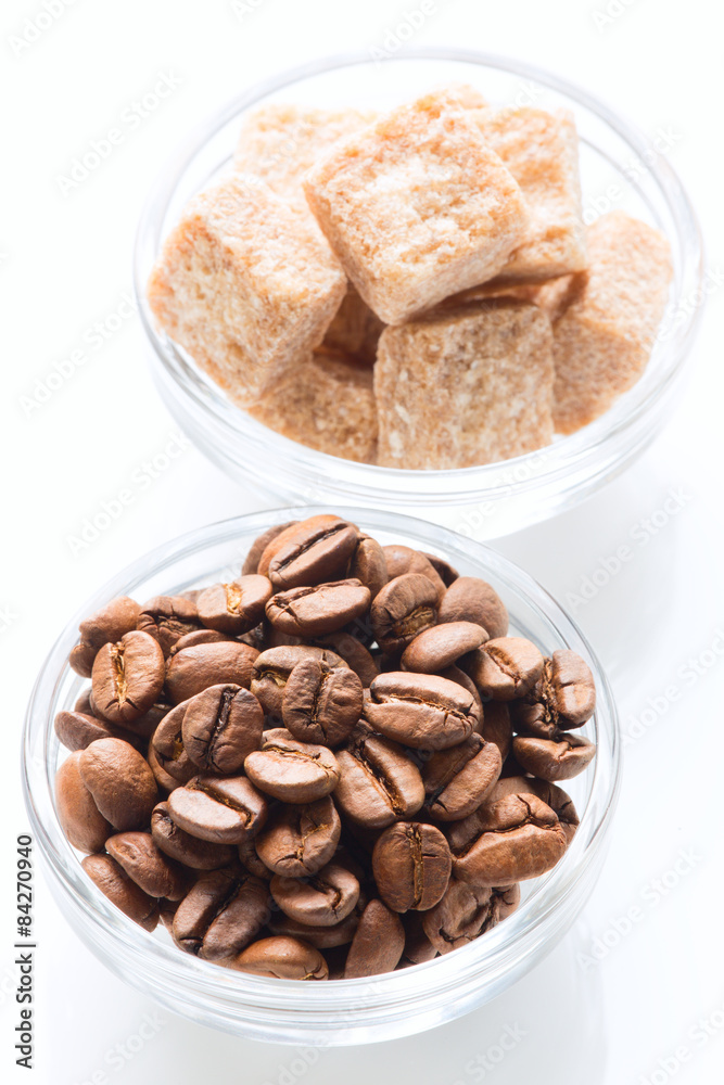 Roasted coffee beans and raw sugar cubes Roasted coffee beans and raw sugar cubes