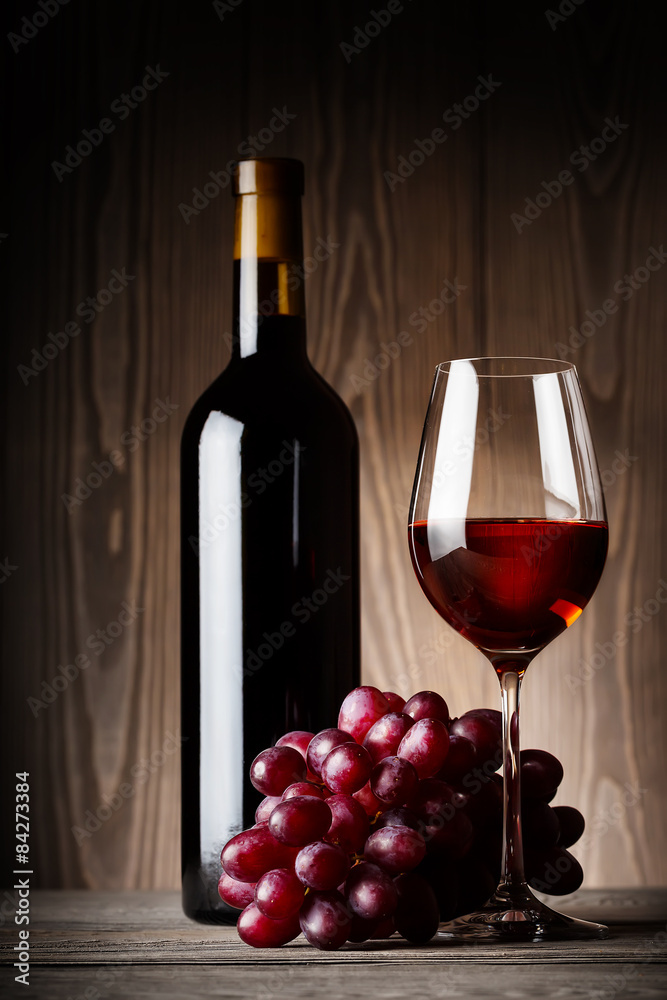 Black bottle and glass of red wine with grapes