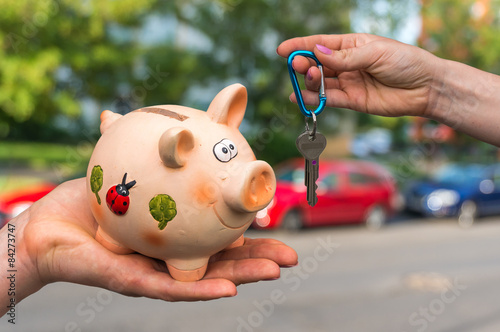 Salesman giving car keys to a new car owner, who is paying all s photo