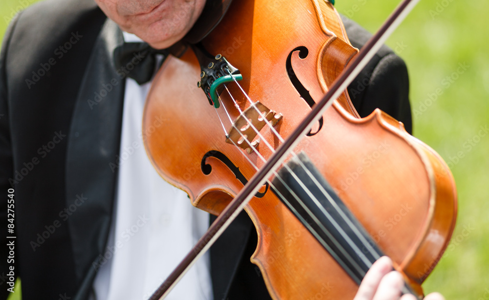 Musician with bow tie plays violin outdoors Musician with bow tie plays violin outdoors