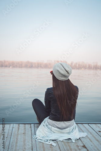 Girl sitting on pier and lookingat the river photo