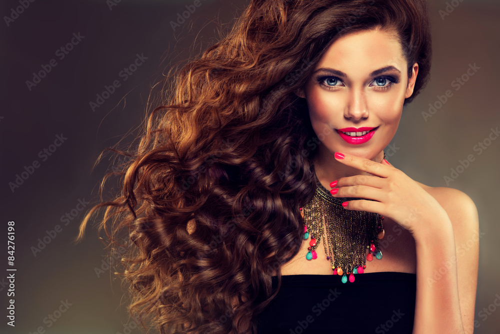 Fototapeta premium Beautiful model brunette with long curled hair. 