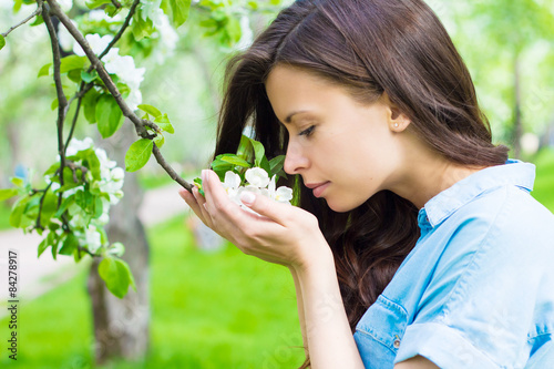 Young woman is smelling apple flower