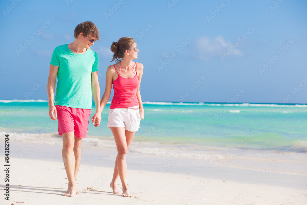 back view of happy romantic young couple hugging on the beach