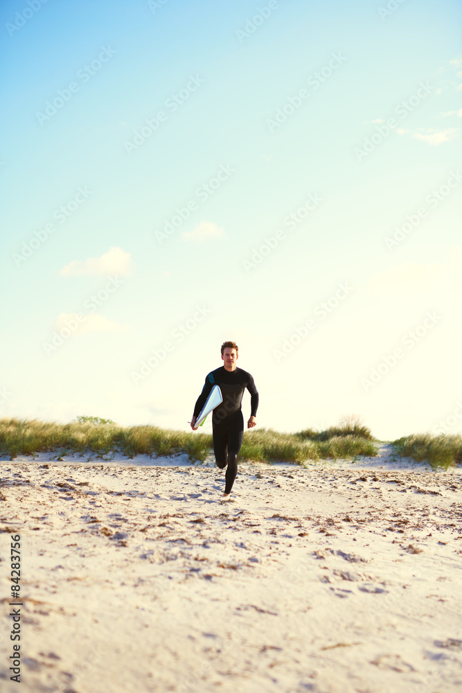 Athletic surfer running towards the surf Athletic surfer running towards the surf