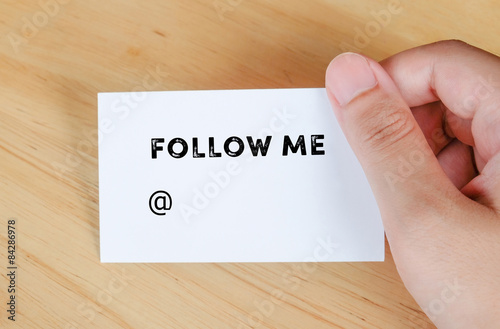 Follow me text on name card in hand