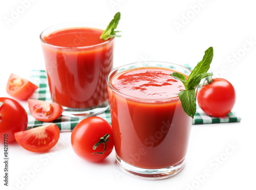 Glasses of fresh tomato juice on checkered napkin  isolated on white