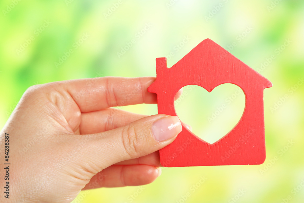 Female hand holding model of house on bright background Female hand holding model of house on bright background