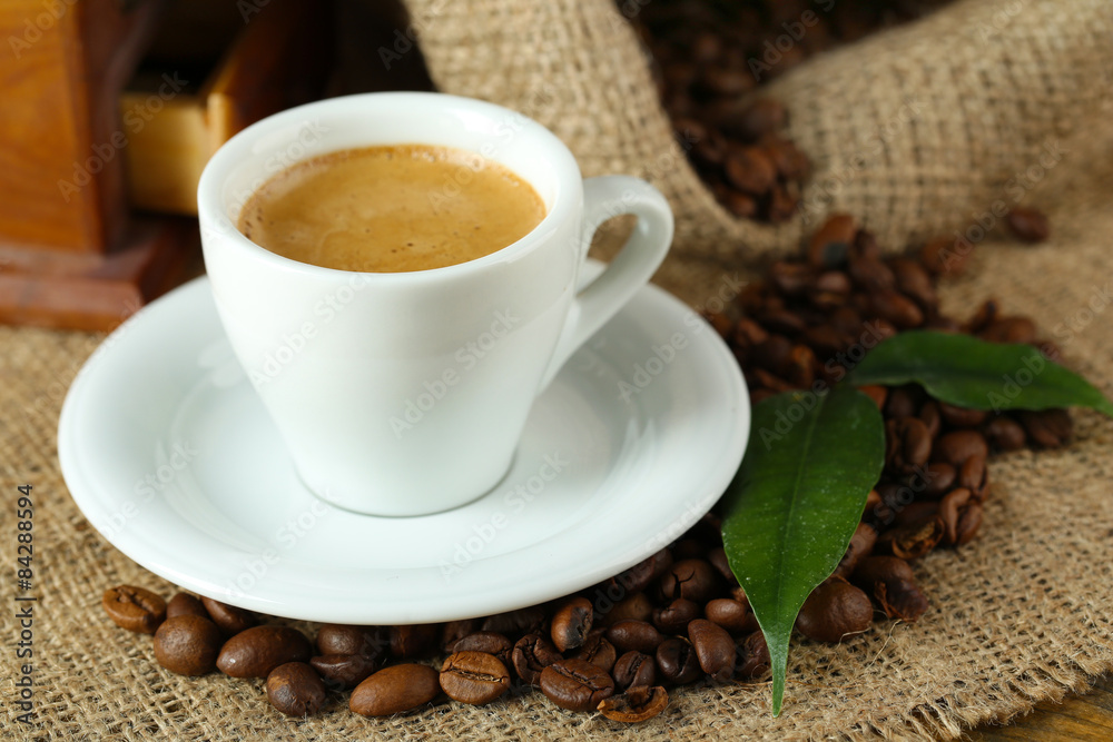 Fototapeta premium Cup of coffee with beans on table close up