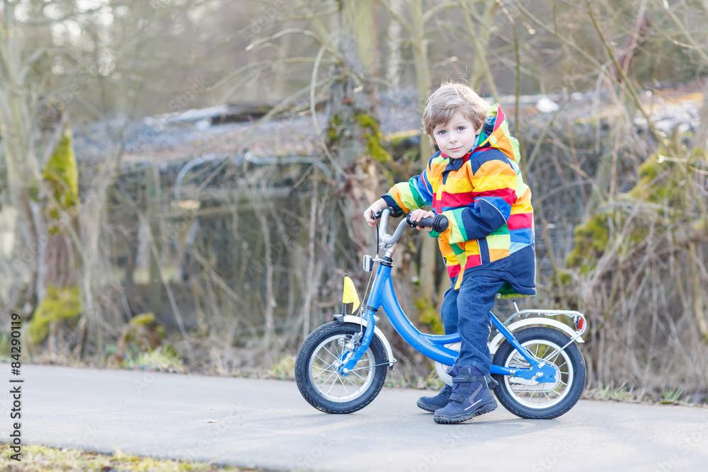kid boy in safety helmet and colorful raincoat riding bike, outd kid boy in safety helmet and colorful raincoat riding bike, outd