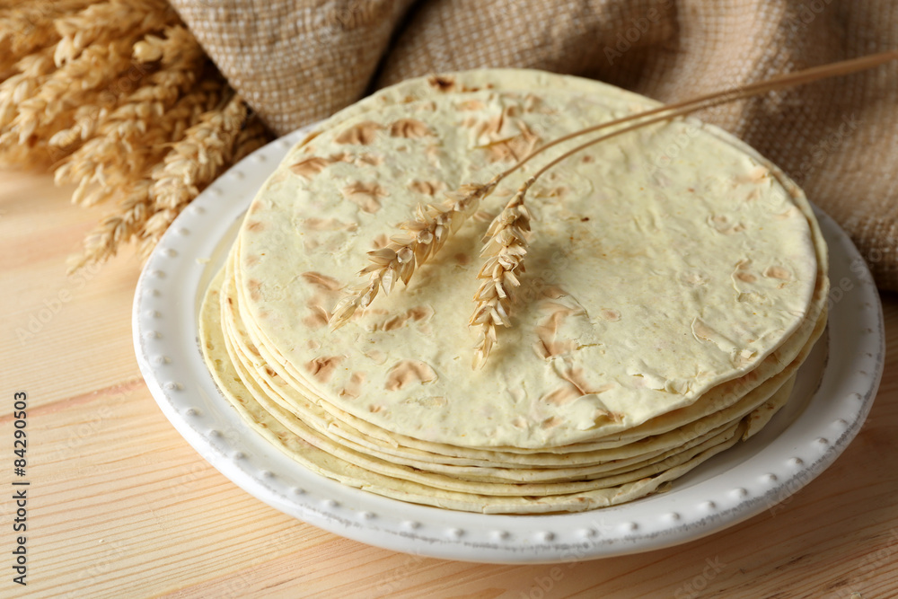 Stack of homemade whole wheat flour tortilla on plate, on wooden table background Stack of homemade whole wheat flour tortilla on plate, on wooden table background