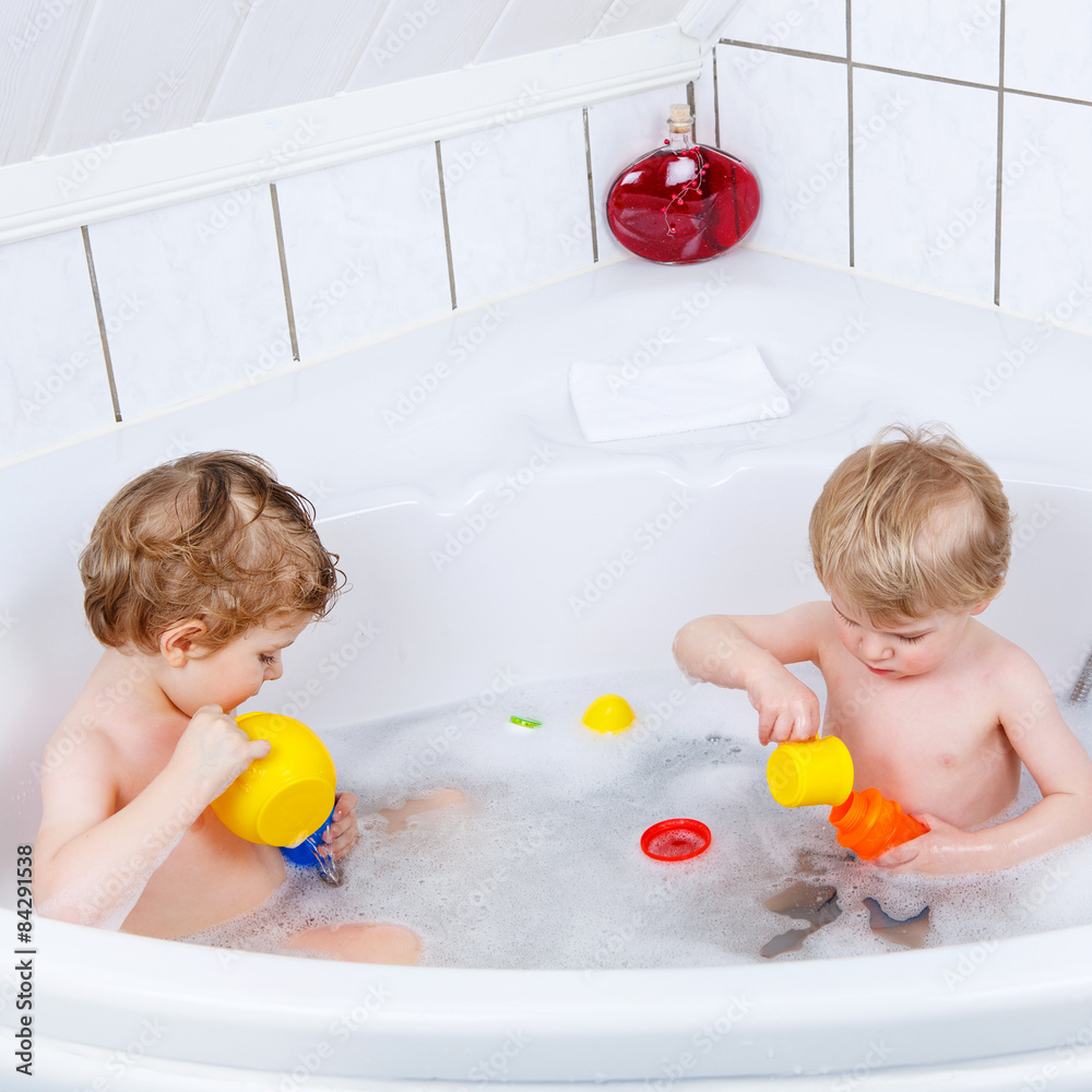 Two little sibling boys having fun with water by taking bath in Two little sibling boys having fun with water by taking bath in