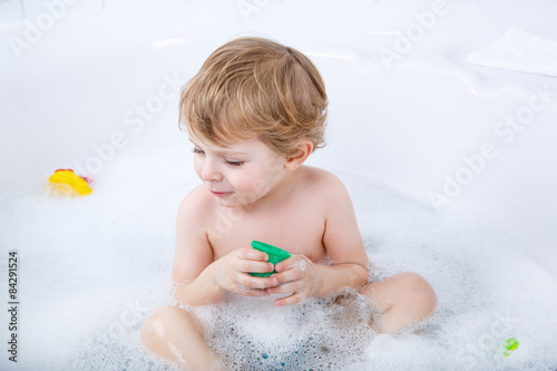 Adorable toddler boy having fun in bathtub