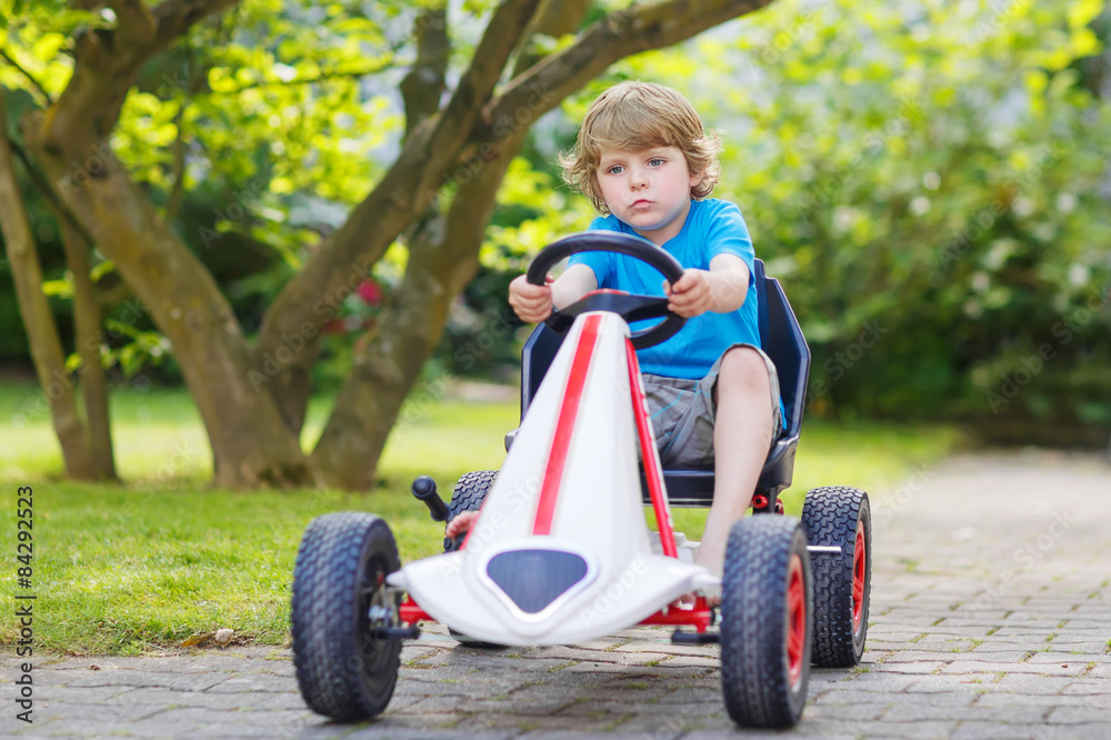 Active little boy having fun and driving toy race car Active little boy having fun and driving toy race car