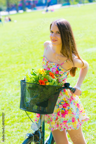 Young woman in short colorful dress with long hair rides a bicyc