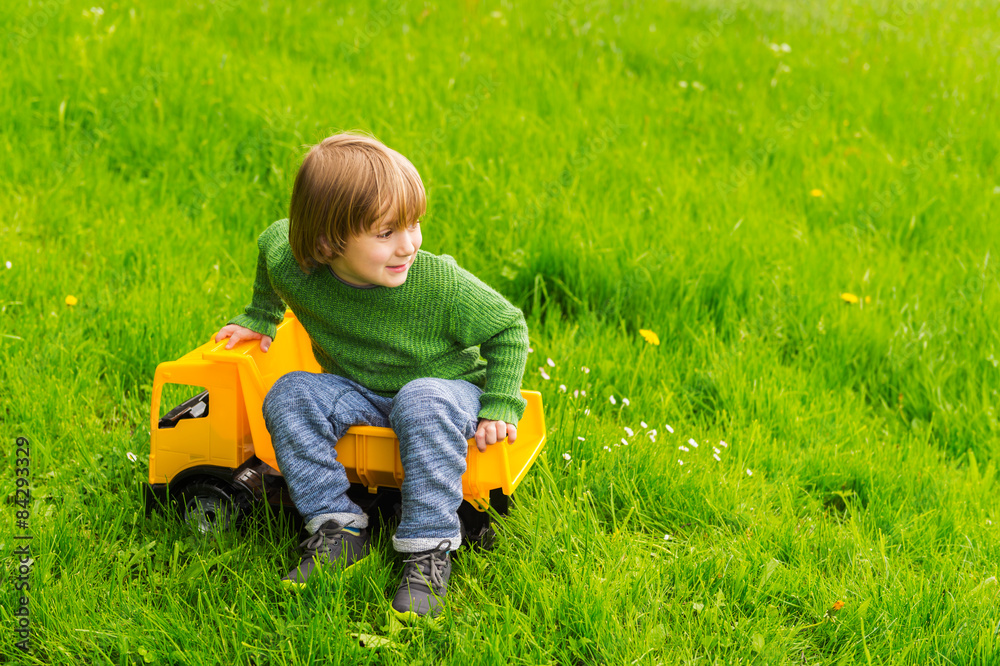 Cute little boy playing with a big yellow toy car Cute little boy playing with a big yellow toy car