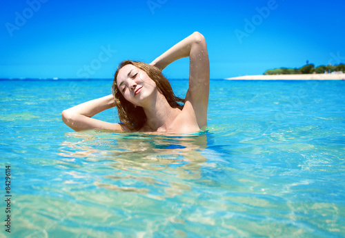 Young girl in bikini swimming on a tropical beach