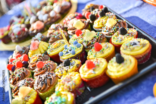 Delicious colorful cupcakes with a birthday candle are on a plat