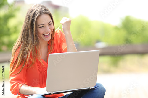 Принти на полотні Euphoric woman searching job with a laptop in a park