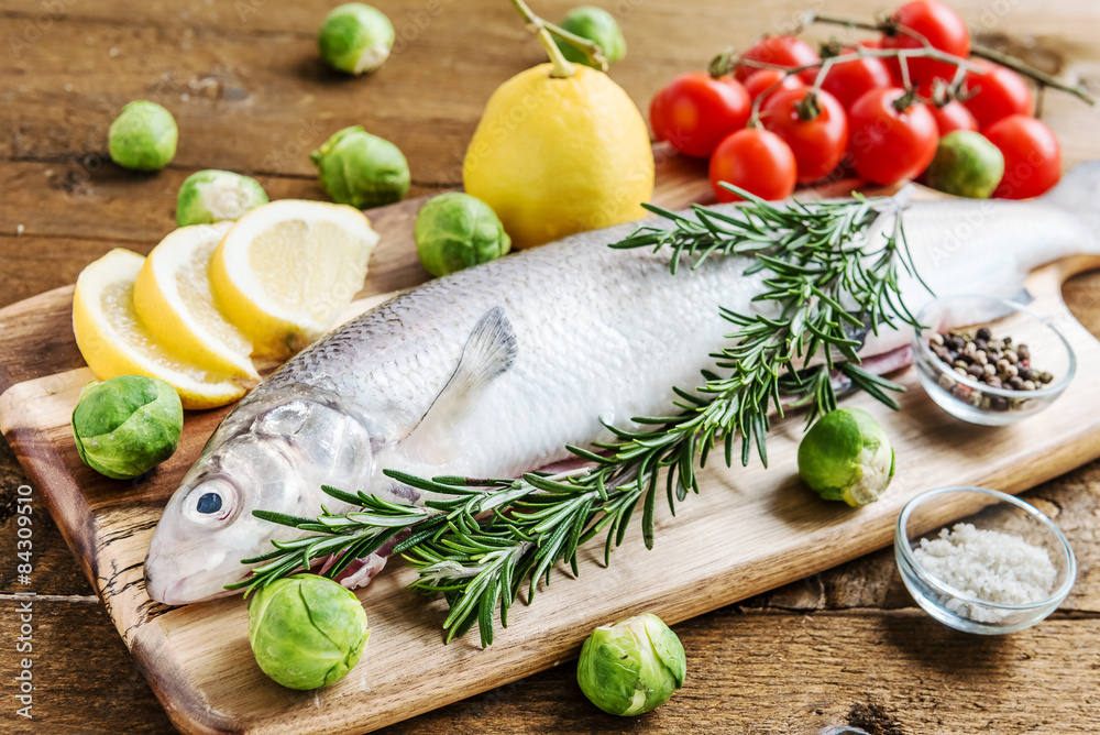 Fresh fish with vegetables and spices on wooden board Fresh fish with vegetables and spices on wooden board